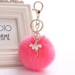 Pink faux fur pompom keychain with a sparkling rhinestone ballerina charm on white background
