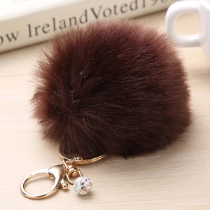 Détail d'un pompon en fausse fourrure marron avec fermoir doré et pendentif boule strass