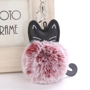 Detail of cute black faux leather cat head with burgundy and white plush pom-pom keychain