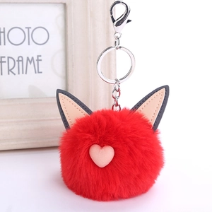 Detail view of a fluffy red faux fur cat ear keychain with soft texture and heart accent