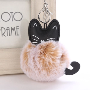 Detail of a fluffy faux fur cat keychain with brown pom pom and leather kitten ears