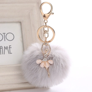 Close-up of fluffy grey pompom keychain with a rhinestone ballerina pendant and gold ring