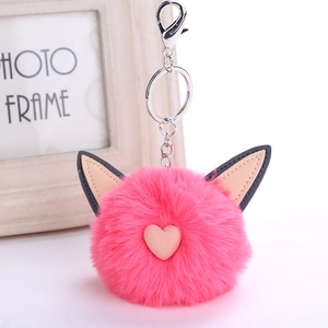 Close-up of bright pink faux fur pompom keychain with cat ears and a small heart detail
