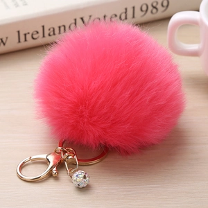 Détail du porte-clés pompon en fausse fourrure rose avec fermoir doré et boule de strass
