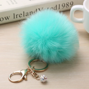 Détail de porte-clés pompon en fausse fourrure vert menthe avec fermoir doré brillant