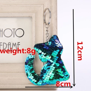 Detail view of a cat sequin keychain in blue-green gradient with dimension markings