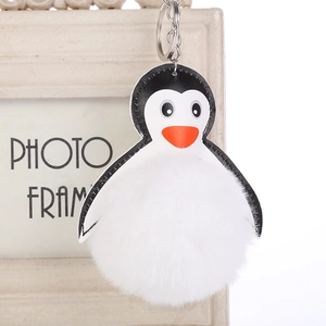 Detalle de un llavero de pingüino de peluche con gran bola de pelo blanca y cuero