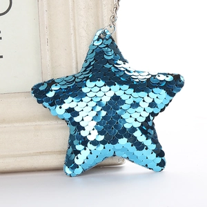 Vue détaillée du porte-clés étoile en paillettes bleu mer avec anneau sur fond crème