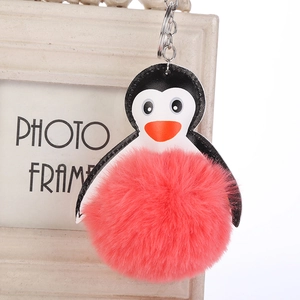 Detalle de llavero de pingüino con pompón de pelo rosa y anilla de metal plateado