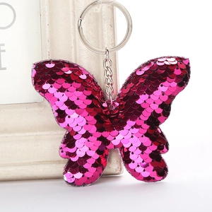 Detailed view of magenta sequin butterfly keychain hanging on a white decorative frame