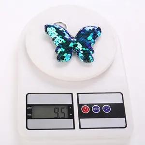 Sparkling blue green gradient sequin butterfly keychain shown on a digital scale weighing 9.5g