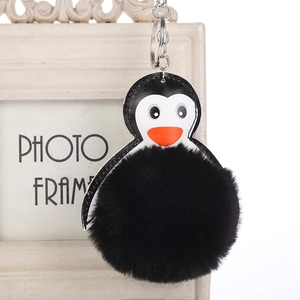 Detalle del llavero de pingüino con pompón de piel negra y anillo de metal plateado