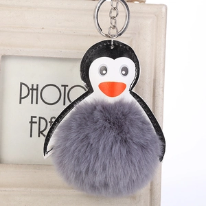 Primer plano del llavero de pingüino con pompón de piel sintética gris y aro plateado