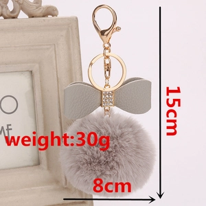 Detail of grey faux fur pompom keychain with rhinestone bow and gold metal clasp