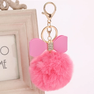 Detail of pink faux fur pompom keychain with a rhinestone studded leather bow