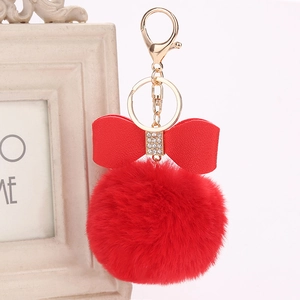Close-up of red rabbit fur ball keychain with rhinestone bow and golden metal clasp