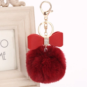 Detail of red faux fur pompom keychain with crystal bow and golden lobster clasp