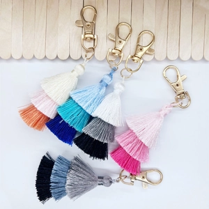 Detailed macro view showing five variants of multi-layered gradient cotton tassel keychains