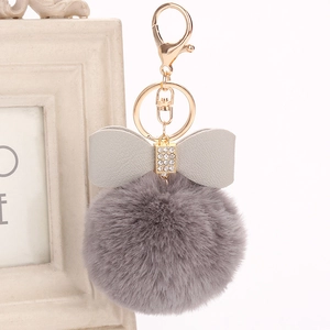 Detail of dark grey faux fur keychain with rhinestone bow and gold lobster clasp