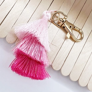 Detail of pink gradient cotton tassel keychain with three-tier design and gold lobster clasp