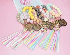 Dettaglio di bracciali con perline leopardate, ciondolo MAMA e nappe colorate