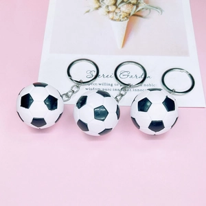 Set of three realistic soccer ball keychains with metallic rings on pink background