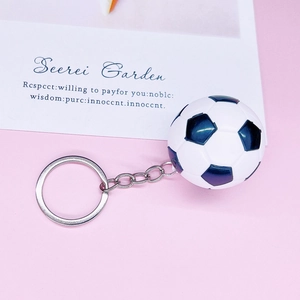 Classic black and white mini football keychain with silver metal chain on pink background