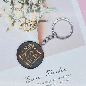 Macro shot of laser-engraved MAMA text on natural wood round charm keychain with silver ring