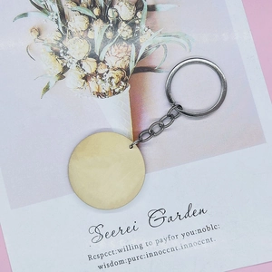Flat lay of round gold blank metal keychain on elegant paper background for laser engraving