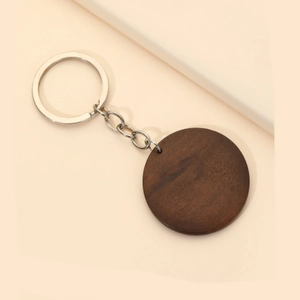 Détail d'un porte-clés rond en bois sombre avec anneau en métal argenté et grain naturel