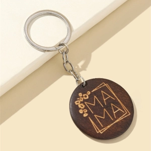 Détail macro du porte-clés rond en bois MAMA avec motifs floraux et anneau en argent