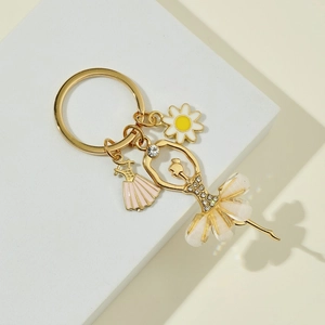 Detailed close-up of golden ballet dancer keychain with rhinestones and floral charms