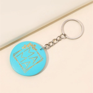 Détail du porte-clés MAMA bleu rond avec lettres dorées et motifs floraux