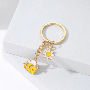 Détails de pendentifs en forme d'abeille et de marguerite dorée sur un porte-clés