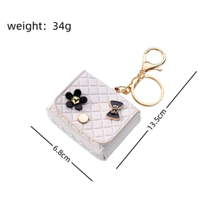 Detail view of mini quilted coin purse keychain with black flower and gold chain