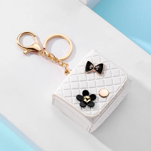 Detail of white quilted leather mini bag keychain with black bow and gold hardware