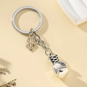Silver boxing glove keychain with dollar sign pendant on a minimalist background