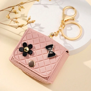 Detailed view of pink quilted leather mini bag keychain with black flower and gold hardware