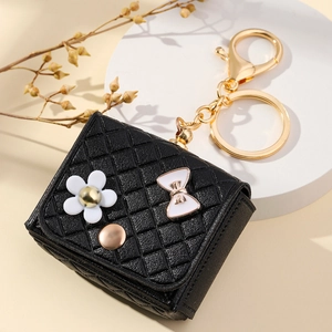 Detail of mini black quilted leather keychain with floral charm and gold clasp