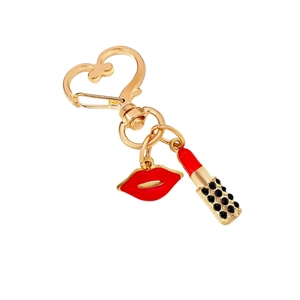 Fashionable gold heart keychain with red lips and lipstick charms on a white background