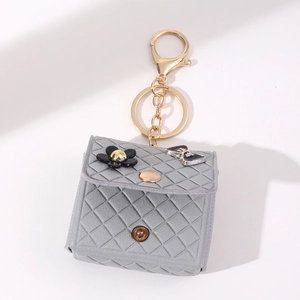 Grey quilted mini bag keychain with gold hardware and flower ribbon charms for bags