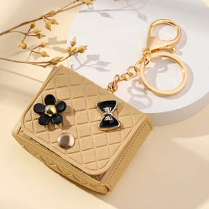 Mini khaki quilted bag pendant with black floral accents and gold keychain hardware