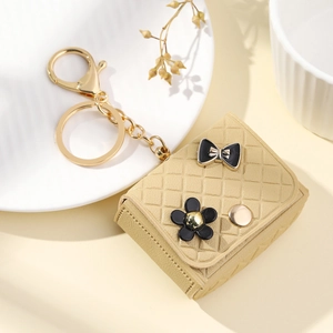 Elegant beige quilted leather mini keychain bag with floral charms and gold hook