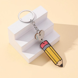 Close-up of pencil and heart pendant keychain on a geometric white display stand