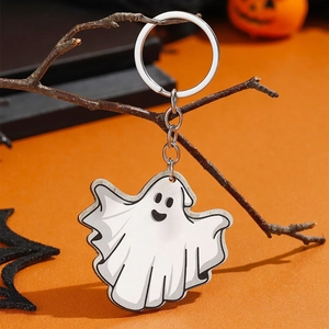 Close-up van een witte spook sleutelhanger aan een tak met een oranje Halloween achtergrond