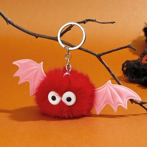 Détail d'un porte-clés chauve-souris en fausse fourrure rouge avec des ailes roses