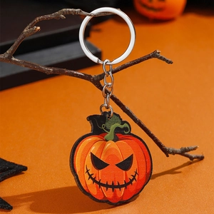 Halloween pompoen sleutelhanger hangend aan een tak tegen een warme oranje achtergrond