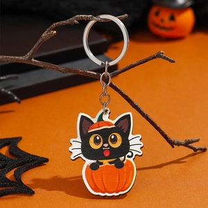 Detail van Halloween-sleutelhanger met zwarte kat in een pompoen op oranje achtergrond