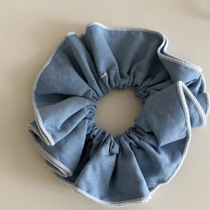 Chouchou bleu esthétique avec bords surjetés blancs sur un fond neutre beige