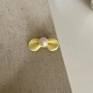 Süße gelbe Schleifen-Haarspange mit Perle für Frauen, präsentiert auf neutralem Grund
